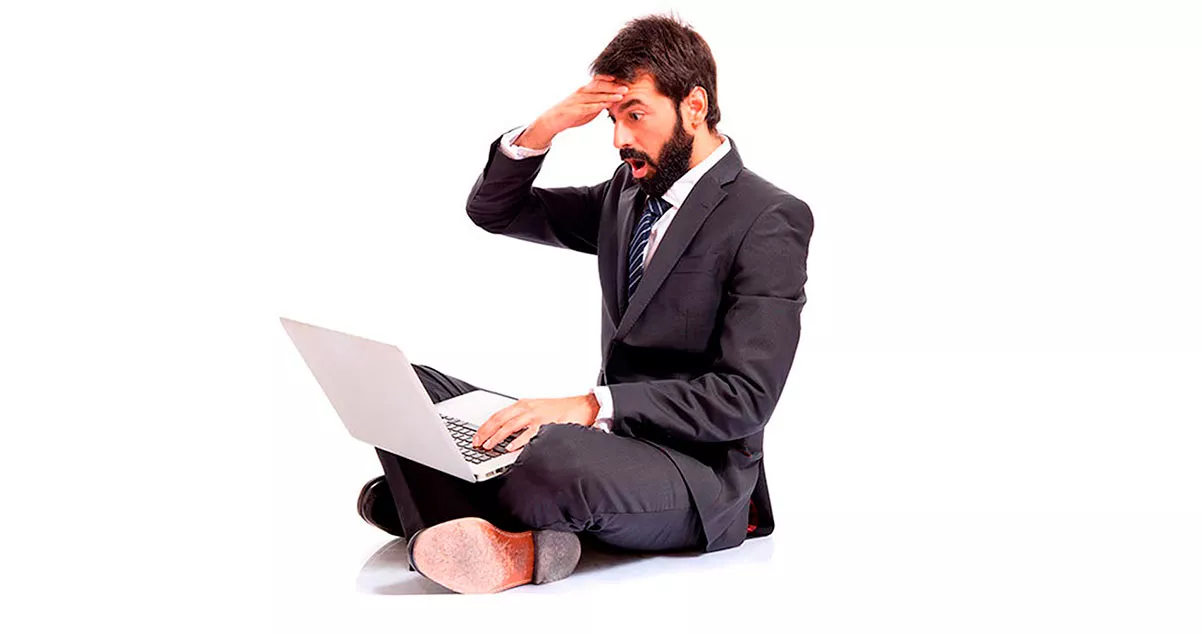 Hombre revisando información en su portátil con gesto de asombro